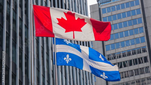 Quebec and Canada flags fluttering in the wind together in the downtown of Montreal. photo