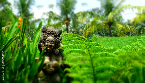 Bali statue sits in lush gardens.