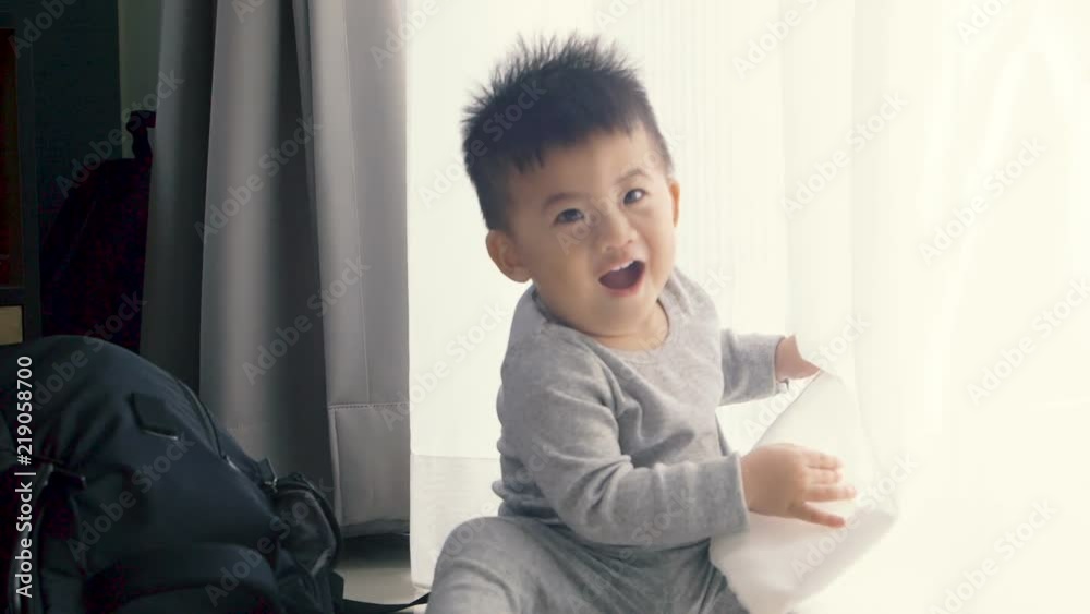 Baby boy sitting and playing curtain at the window, Kids and nursery curtains concept, Slow motion Baby boy sitting and playing curtain at the window, Kids and nursery curtains concept, Slow motion