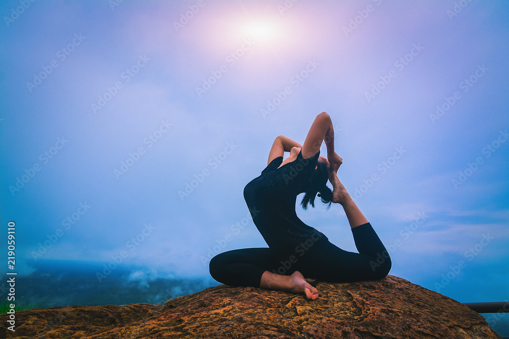 Young girl doing yoga fitness exercise outdoor in beautiful mountains landscape. Morning sunrise