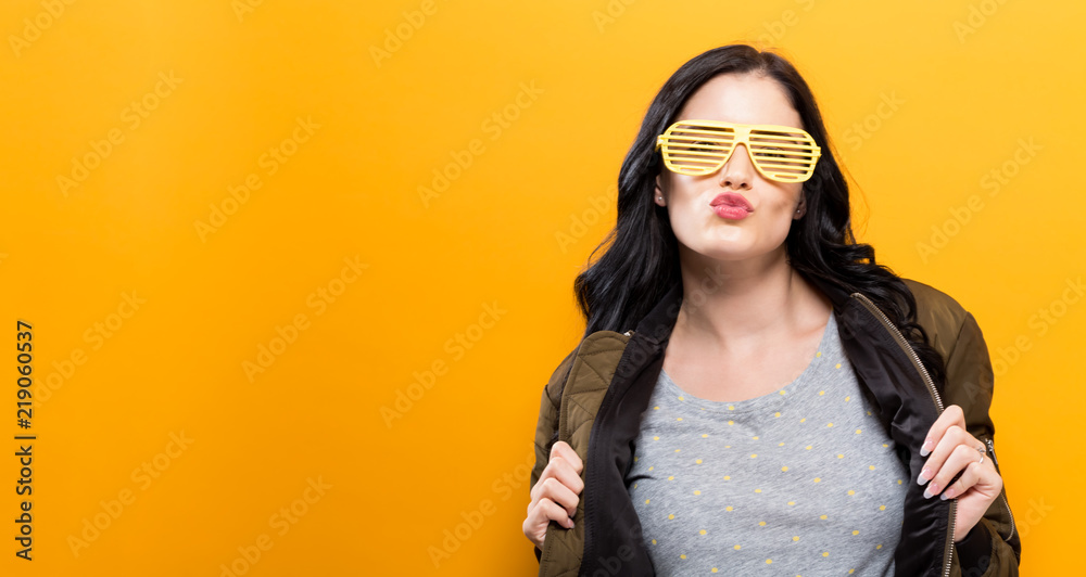 Fashionable woman with attitude in a bomber jacket on a golden yellow background