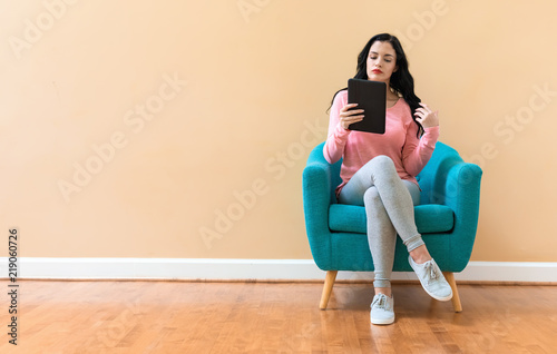 Young woman using her tablet on a blue chair