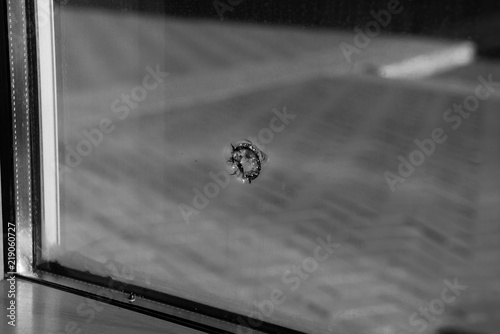 Black and white glass with bullet hole