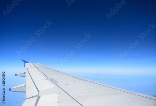 Wing of an airplane flying and Blue sky background with beautiful clouds in sky. View from the window airplane flying.