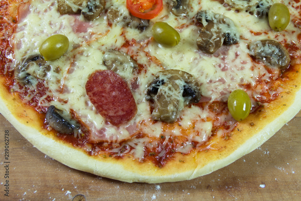 Hot appetite baked pizza. Variety of attachments on the wooden table Hot appetite baked pizza. Variety of attachments on the wooden table