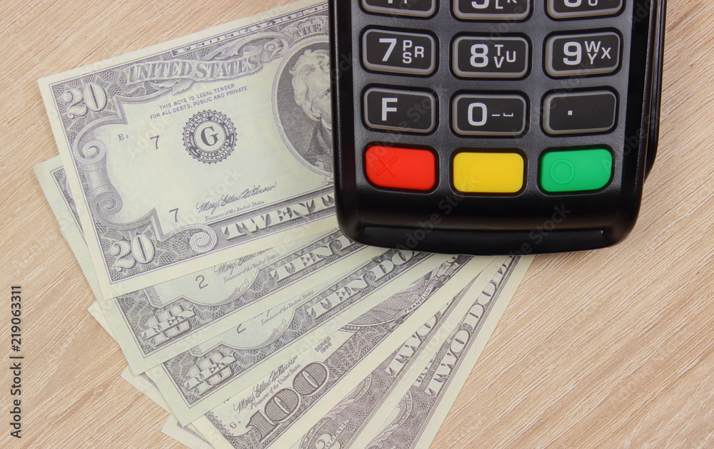 Payment terminal with currencies dollar, credit card machine on desk, finance concept Payment terminal with currencies dollar, credit card machine on desk, finance concept