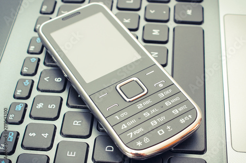 Mobile phone lying on laptop keyboard, electronics
