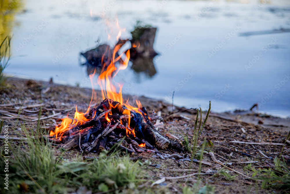 Beautiful campfire in the evening at lake. Fire burning in dusk at campsite Beautiful campfire in the evening at lake. Fire burning in dusk at campsite