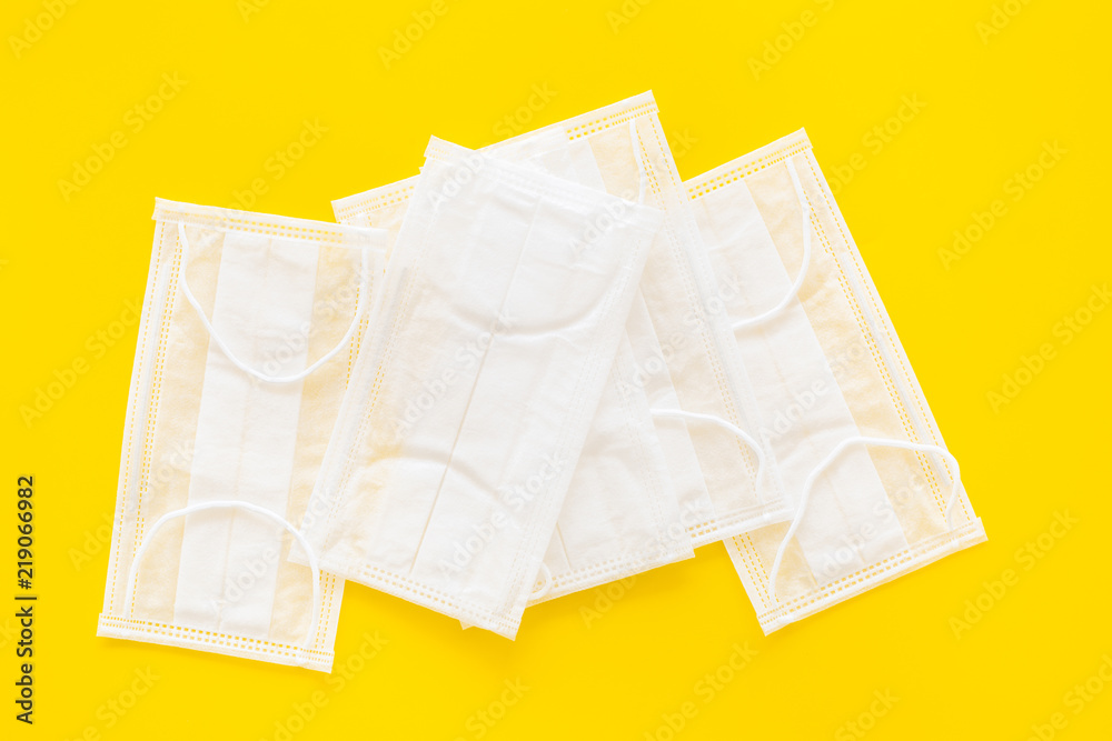 Flu prevention. Medical face masks on yellow background top view copy space