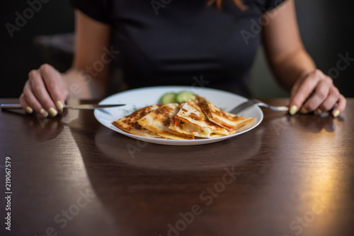 Woman eating delicious quesadilla in restaurant. Mexican food snacks, fast food preparation for commercial kitchens.