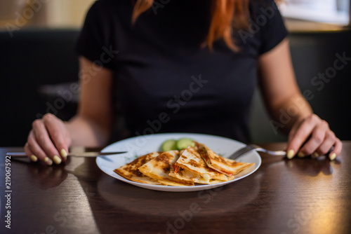 Woman eating delicious quesadilla in restaurant. Woman eating delicious quesadilla in restaurant. Young redheaded woman is eating Mexican food in a cafe