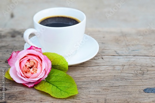 close up shot,black coffee in white coffee cup and beautiful pink rose on blue and old rustic wood background, morning breakfast concept, top view with copy space for text
