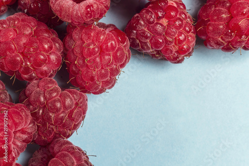 Fresh raspberries on blue background with copy space.