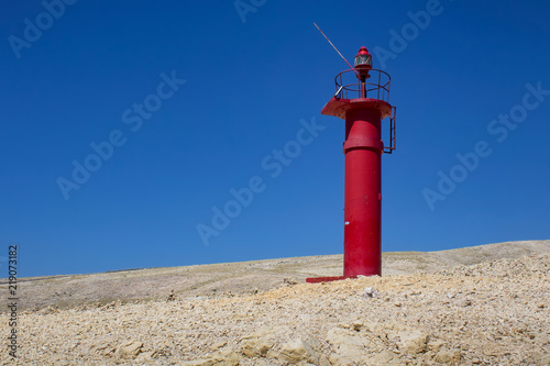 Red lighthouse on rock with blue sky  island Krk  Croatia