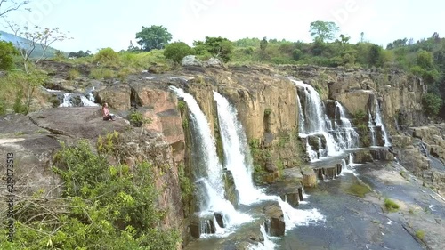 famous waterfall with many streams and girl sits on cliff photo