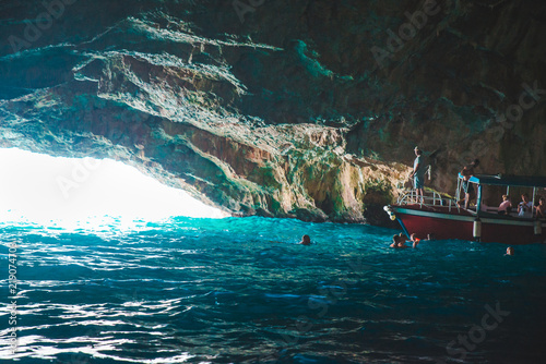 boat with group of tourists in beautiful grotto with azure transparent water