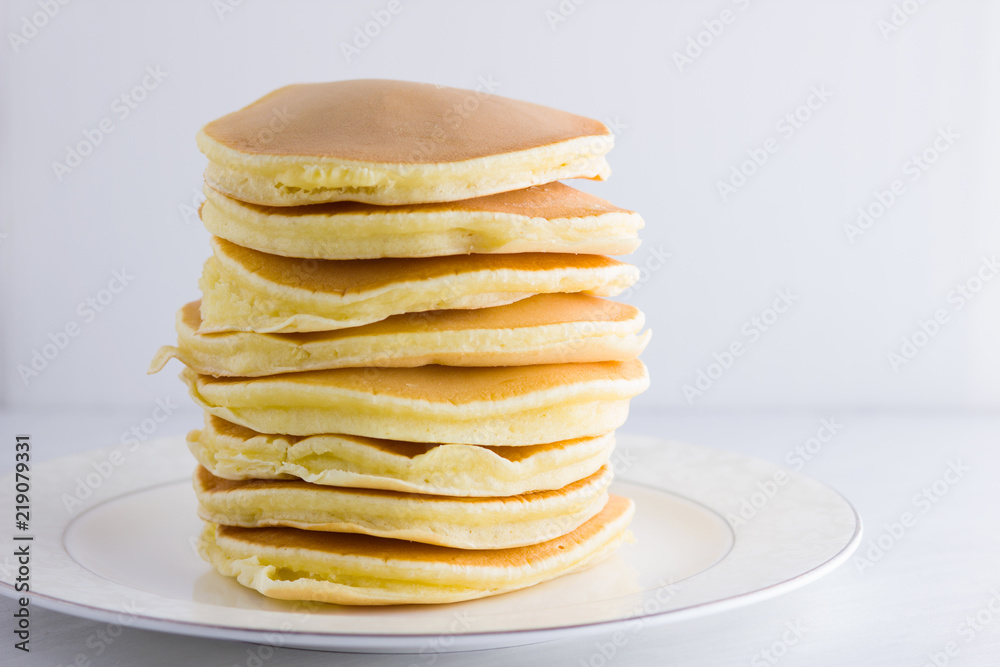 Pancakes on a white background. Many pancakes on a white plate with copy space. Delicious dish for breakfast. Festive food Pancakes on a white background. Many pancakes on a white plate with copy space. Delicious dish for breakfast. Festive food