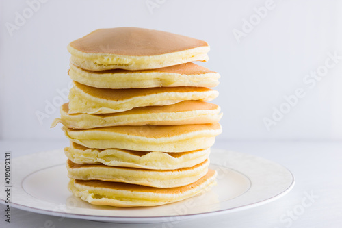 Pancakes on a white background. Many pancakes on a white plate with copy space. Delicious dish for breakfast. Festive food