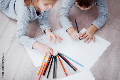 Children lie on the floor in pajamas and draw with pencils. Cute child painting by pencils