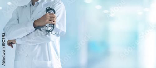 Male medicine doctor with stethoscope in hand standing confidently on hospital background photo