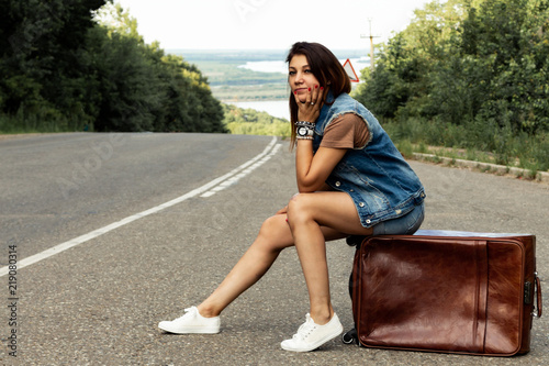 Girl with a suitcase stops the car on the road photo