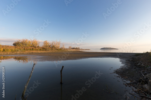 Beautiful view of Trasimeno lake shore  Umbria  Italy   with totally empty blue sky reflecting on water
