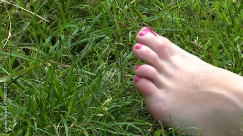 Women's feet are lying in the grass. Legs move with happiness.