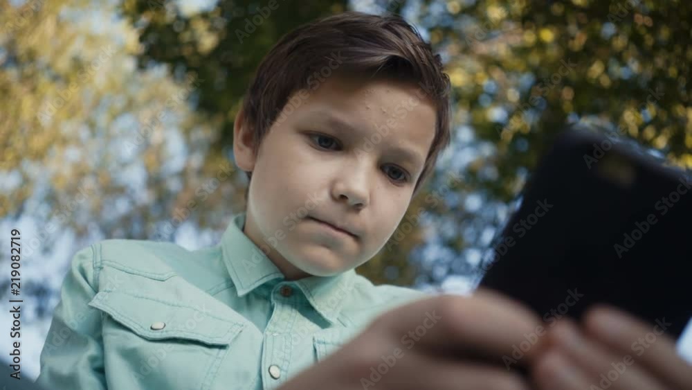 teenager playing video games on his smartphone outdoors. teenager playing video games on his smartphone outdoors.