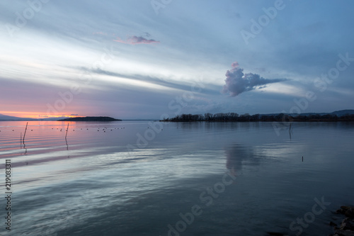 A shoot of a sunset over a lake, with beautiful warm colors and clouds and perfectly symmetryc reflections