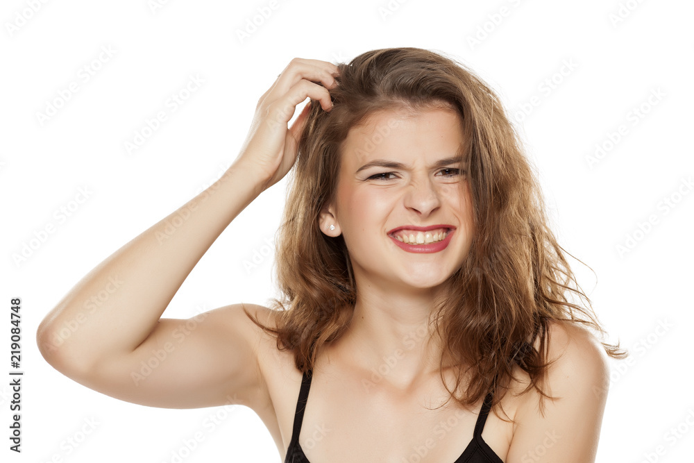 Young woman scratching her head on white background