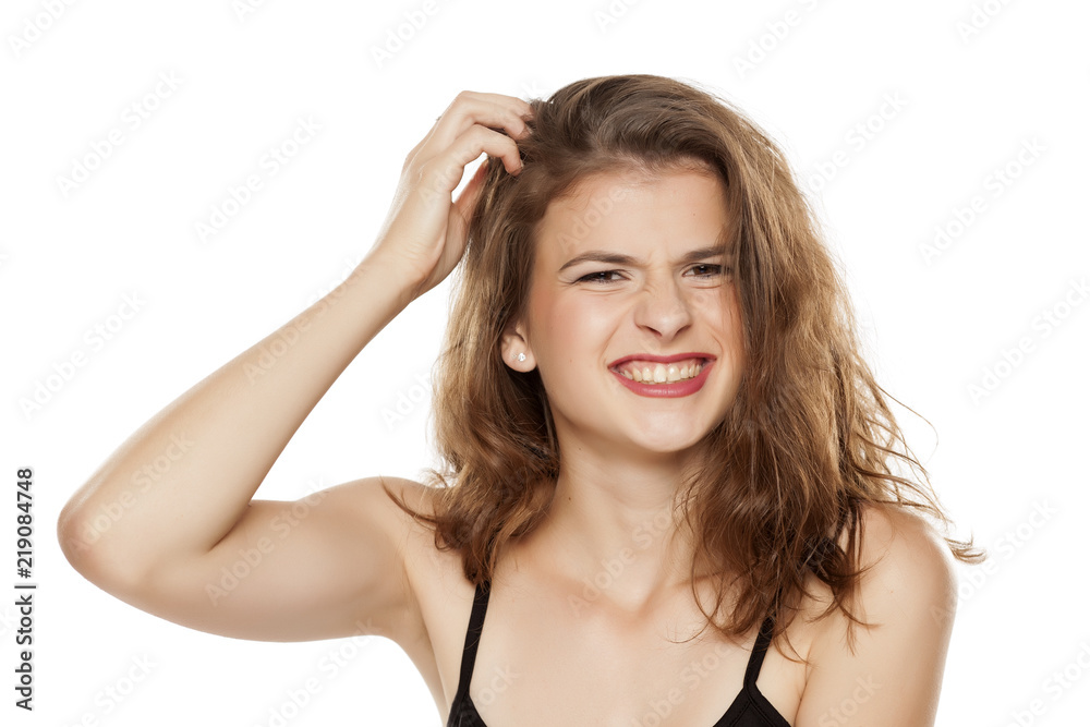 Young woman scratching her head on white background Young woman scratching her head on white background
