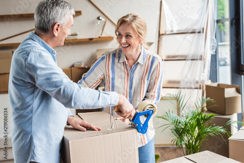 happy elderly couple packing cardboard boxes during relocation photo