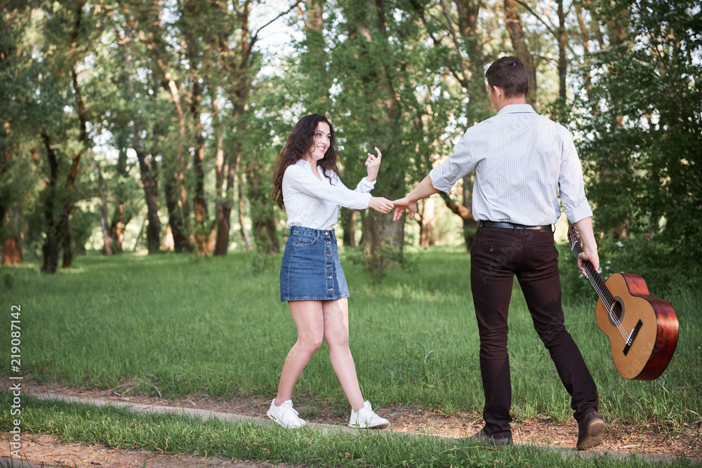 young couple walking in the forest and playing guitar, summer nature, bright sunlight, shadows and green leaves, romantic feelings young couple walking in the forest and playing guitar, summer nature, bright sunlight, shadows and green leaves, romantic feelings