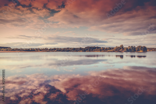 Beautiful pink sunset on the lake, clouds reflected in the water, beautiful autumn landscape