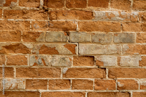 Photo of an ancient wall of red clay brick with a calcareous solution during the restoration. The crack split the old brick wall. Restoration of the broken brick wall of the 1600s.
