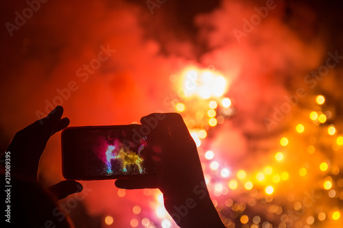 Hands hold a mobile phone and record ground fireworks 