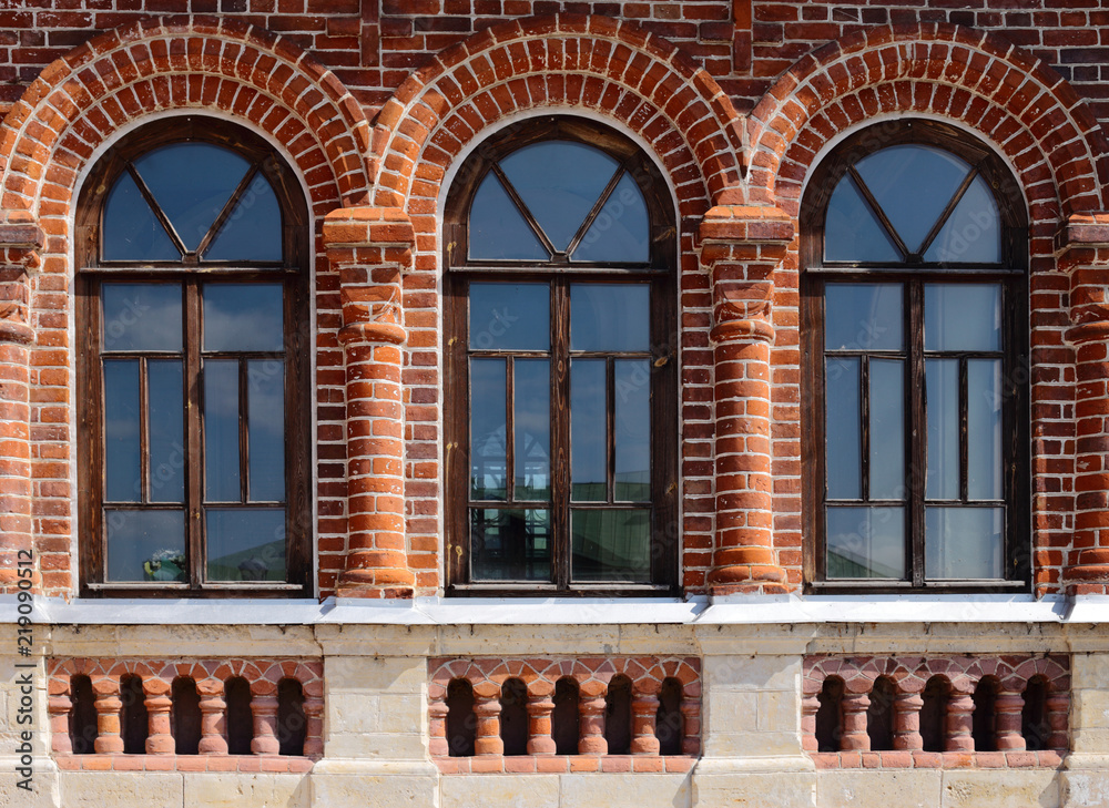 the wall of an old red brick building. There are three windows in the form  of an arch. Stock Photo | Adobe Stock