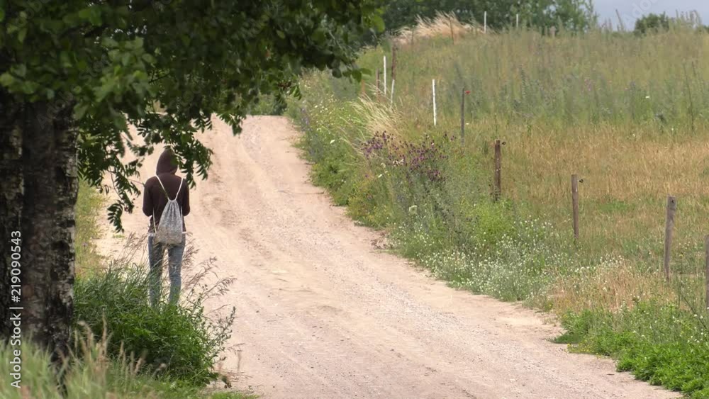A woman walks along a dirt road. Reads a book. Grass and trees in the background. Panning,Closeup, A woman walks along a dirt road. Reads a book. Grass and trees in the background. Panning,Closeup,