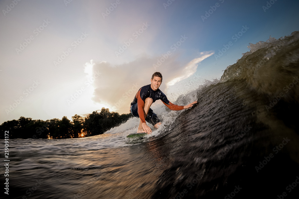Young man standing on the one knee on the wakeboard