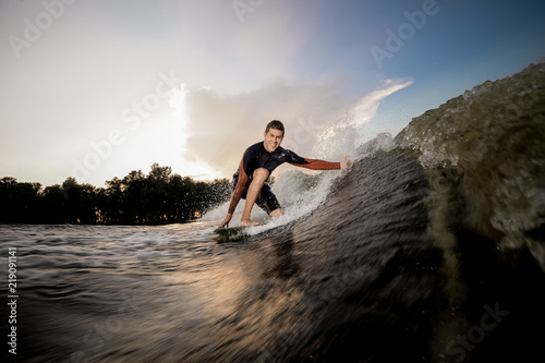 Young attractive man standing on the one knee on the wakeboard