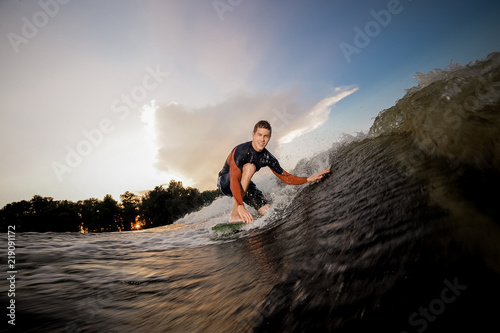 Young man standing on the one knee on the wakeboard