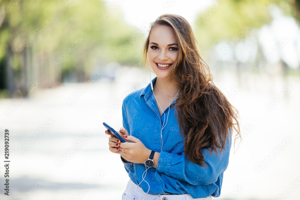 Cheerful woman in the street use her smartphone. Young woman using phone on the street. Cheerful woman in the street use her smartphone. Young woman using phone on the street.