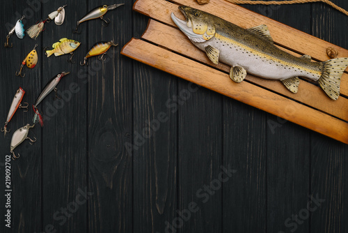 Fishing tackle - fishing spinning, hooks and lures on darken wooden background. Top view. photo