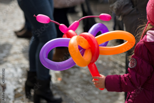 A small girl holding a balloon butterfly or dog that she got as a gift for her birthday party at a children party from clown  
