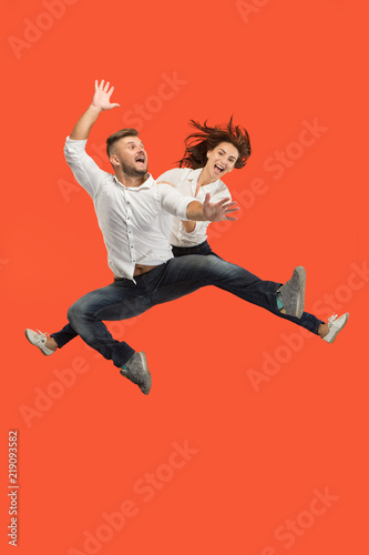 Freedom in moving. Pretty young couple jumping against red background