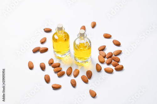 Bottles of almond oil and almonds  on white background  copyspace.