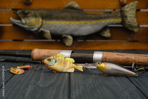 Fishing tackle - fishing spinning, hooks and lures on darken wooden background. Top view. photo