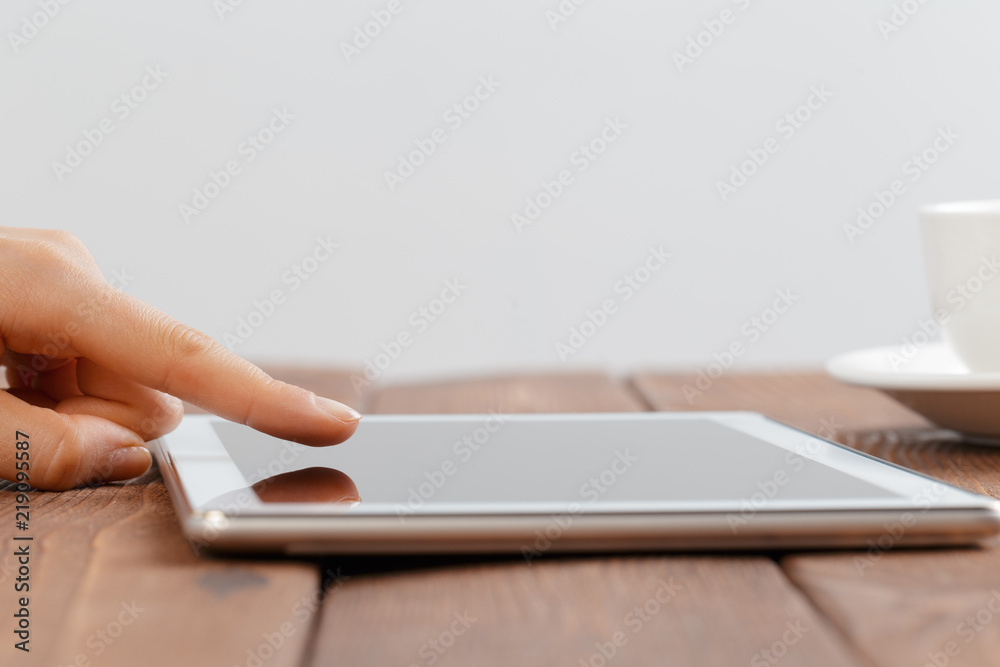 woman holding blank tablet device over a wooden workspace table woman holding blank tablet device over a wooden workspace table
