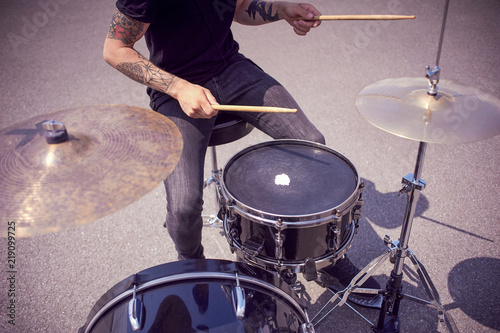 cropped shot of tattooed drummer playing drums on street