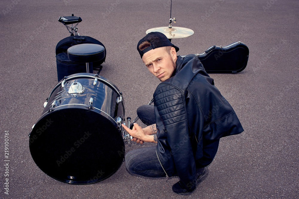 Fototapeta premium Drummer in black clothing pointing at drum kit on street